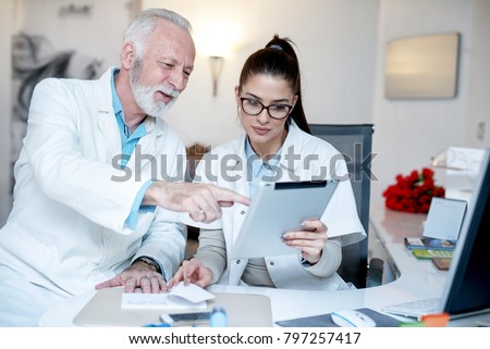 Doctor is explaining something to his assistant with the help of tablet comuter.  Royalty-Free Stock Photo #797257417
