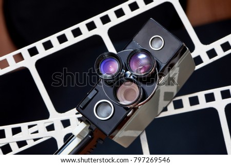Old retro movie camera on background of perforation film