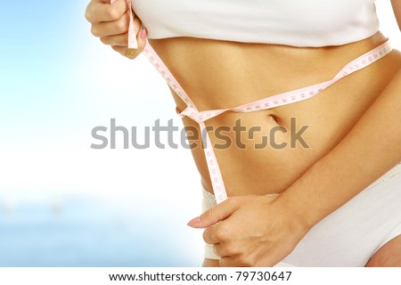 A slim girl measuring her waist, closeup, isolated on white Royalty-Free Stock Photo #79730647