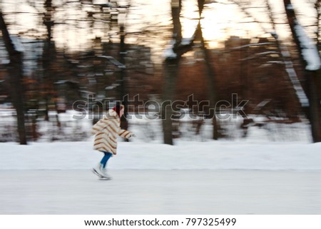 Girl in a striped fur coat skates at sunset