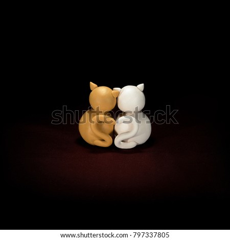 Two minimalistic animal figures in love. Lovely cat plasticine models having tails in heart shape isolated on dark red background. Happy Valentine's Day in minimalism style.