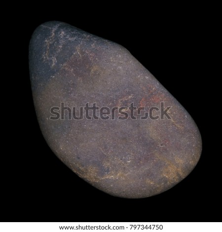 A high resolution macro close up of a grey pebble or stone isolated against a black background