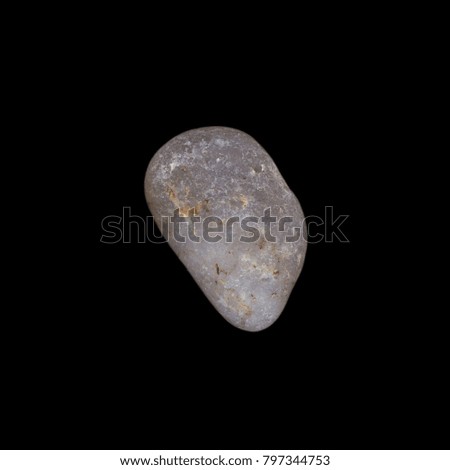 A high resolution macro close up of a grey pebble or stone isolated against a black background