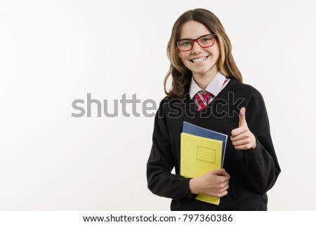 Girl teenager, high school student, smiling on white background, in school uniform and showing thumbs up. Copy space