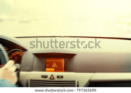 Slippery road warning on car display, car interior point of view