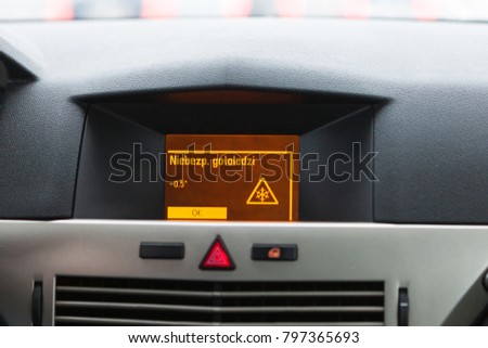 "Danger of ice" warning on car display, car interior point of view
