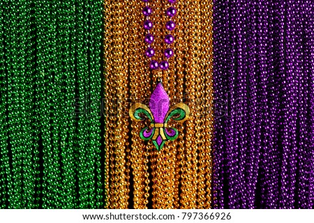 Green, gold, and purple Mardi Gras beads with Fleur de lis background Royalty-Free Stock Photo #797366926
