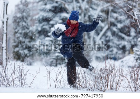 kid jumps and plays snowballs in the winter park
