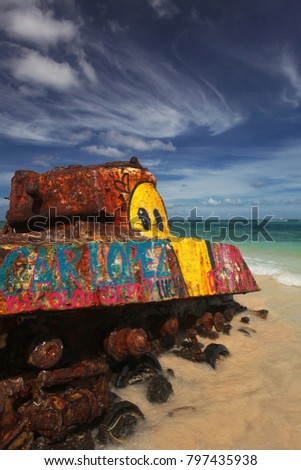 Close-up of a rusted Tank at Flamenco Beach on Culebra Island, Puerto Rico, with turquoise Water and blue Sky - Grafitti saying "(FREE OS)CAR LOPEZ (blue and pink) and "DECOLONISE PR" (pink)