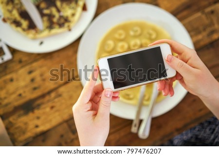 girl takes a picture of food on her phone. Smartphone in the hands of Women. Notes on cooking. Photo of food. Food Blogger.