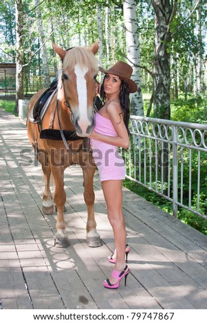 young beautiful woman next to a horse on nature