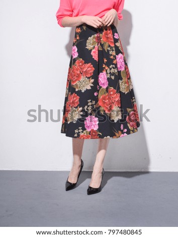 Leg in long floral skirt with black shoes –gray background

