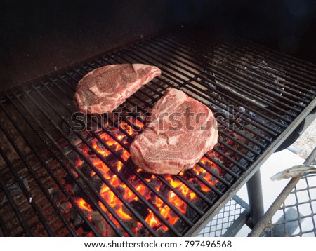 Steaks over glowing coals on a grill