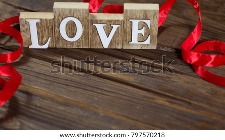 Wooden inscription "Love". With a ribbon in the background