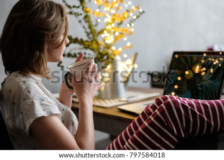 Woman drinking coffee and watching at laptop