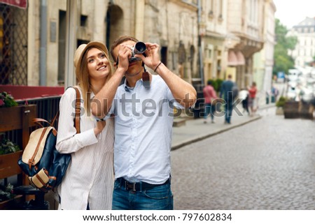 Tourist Couple Taking Photos On Camera On Street. Handsome Young Man And Beautiful Woman Traveling And Making Photos Of City Architecture On Camera. Travel And Sightseeing. High Resolution.