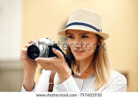 Woman Taking Photos On Camera On Street. Portrait Of Beautiful Smiling Woman In Trendy Hat Making Photo Outdoors, Traveling To Old City. High Resolution.