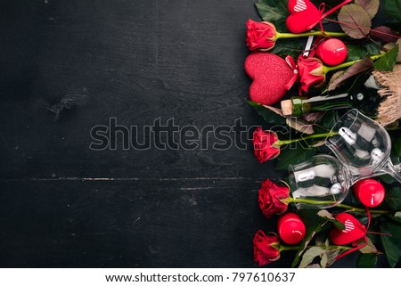 A bottle of red wine and a bouquet of red roses. Valentines day. On a wooden background. Top view. Free space for your text.