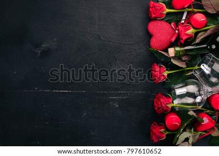 A bottle of red wine and a bouquet of red roses. Valentines day. On a wooden background. Top view. Free space for your text.