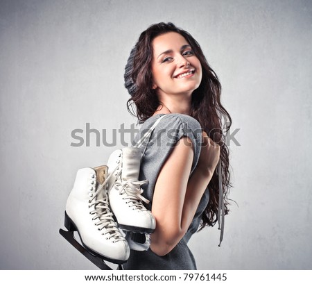 Smiling young woman carrying a pair of ice skates