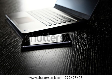 smartphone near a laptop on a wooden table