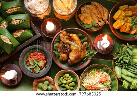 Nasi Tutug Oncom. Traditional Sundanese meal of rice mixed with fermented soybean; accompanied with fried chicken, tempeh, tofu, salted fish, vegetables dishes, chili paste and crackers. Royalty-Free Stock Photo #797685025