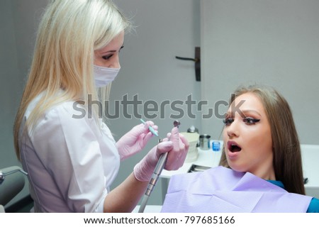Frightened woman sitting in the dentist's chair while studying the doctor her teeth