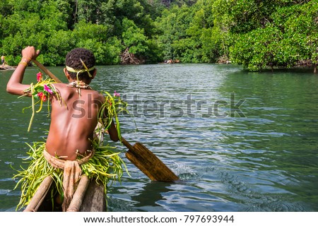 Yang sportive indigenous tribal boy with a paddle in a traditional canoe, natural green jungle with mangrove trees background, Melanesia, Papua New Guinea, Tufi Royalty-Free Stock Photo #797693944