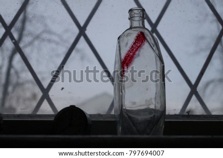 A window with a diamond-shaped lattice. Glass bottle on the windowsill. The glass bottle is of crystalline form.