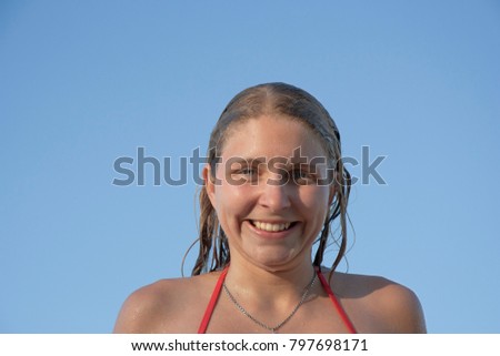 Portrait of a wet young woman in front of a blue sky