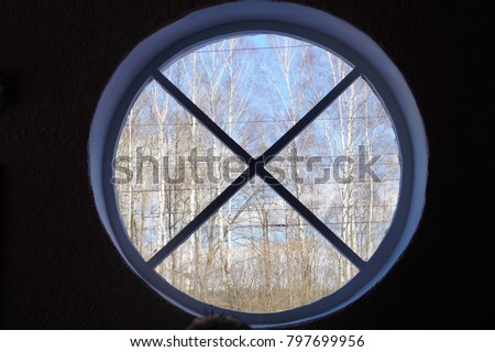  Round window inside the building, view from the window, trees in the form of a window, backlight.