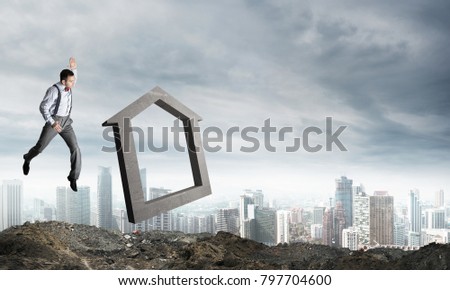 Jumping businessman crashing big house symbol with city view on background. 3D rendering.