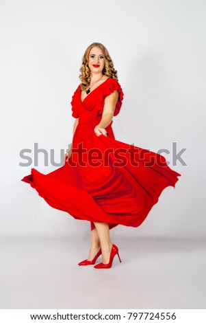 young woman in a red evening dress is danced on a white backgrou