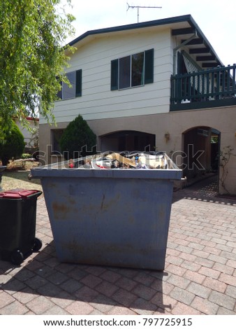 Garbage skip in a front yards of a family suburban home full of waste