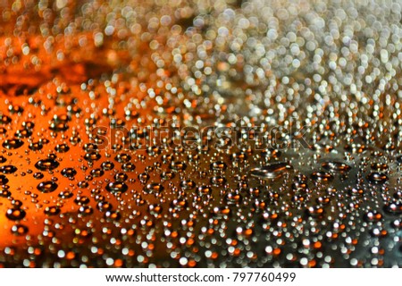 Drops of water on a dark surface in a multicolored light