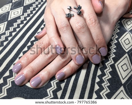 Nail artist. Purple manicure on geometric background.Fashion rings and nails.