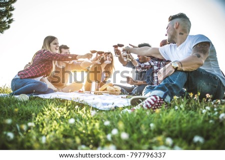 Group of friends having pic-nic in a park on a sunny day - People hanging out having fun while grilling and relaxing
