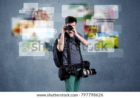 A young professional male photographer holding cameras and taking pictures in front of a blue wall with pictures, icons, text information concept