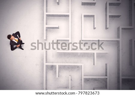 Confused businessman standing at a maze wall with grungy background