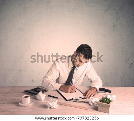A young office worker sitting at desk working with keyboard, papers, highliter in front of empty clear background wall concept