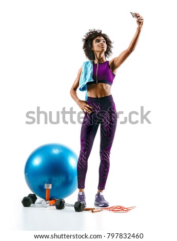 Sporty girl taking selfie pictures on smartphone with sports accesories on white background. Strength and motivation. Full length