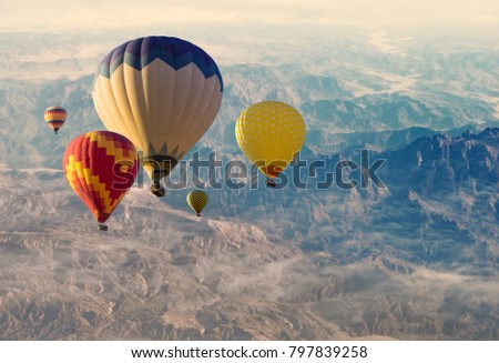 Colorful hot air balloons over mountain peaks background, aerial view. Panoramic landscape for your adventure concept or romantic trip.