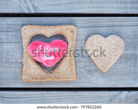 Heart shaped bread and a red heart on wooden plate for Valentine’s Day background.