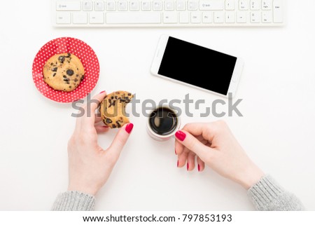 girl holding a cup of coffee, standing next to a plate of cookies, lunch break, white smart phone, top view, background with copy space, for advertising