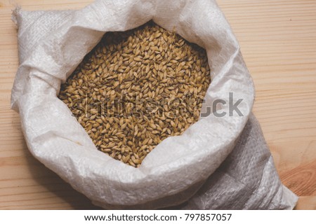 Caramel malt in a bag on a wooden background. Craft beer brewing from grain barley pale malt in process. 