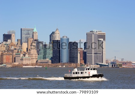 Urban skyscrapers and boat from New York City Manhattan downtown over river.