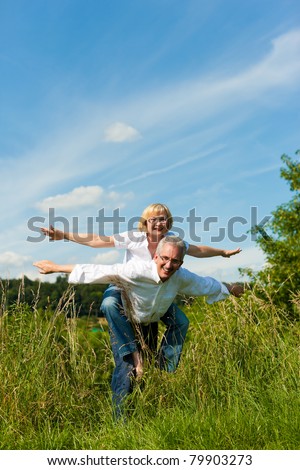 Happy mature couple - senior people (man and woman) already retired - having fun in summer in nature Royalty-Free Stock Photo #79903273