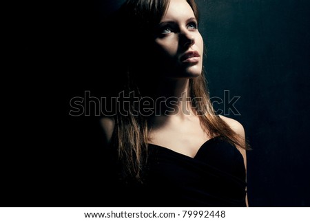 beautiful woman portrait wearing black dress over dark background
