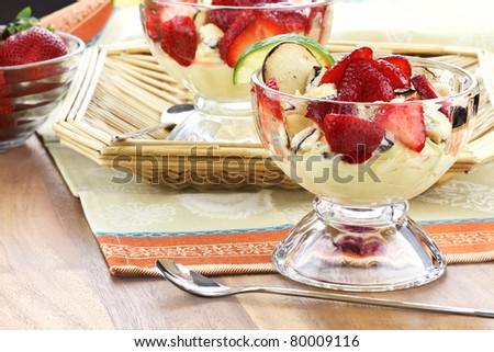 Freeform strawberry cheesecake with cookies and a slice of lime. Shallow depth of field with reflection in wood.