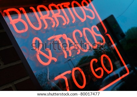 Burritos and tacos to go. Neon store sign on mexican restaurant advertising takeouts